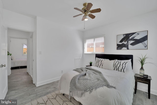 bedroom with light wood-type flooring, a ceiling fan, and baseboards