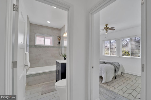 ensuite bathroom featuring baseboards, a ceiling fan, connected bathroom, tiled shower / bath combo, and vanity