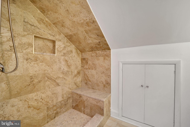 bathroom featuring vaulted ceiling and tiled shower