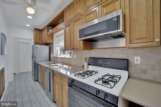 kitchen with light countertops, backsplash, appliances with stainless steel finishes, a sink, and ceiling fan