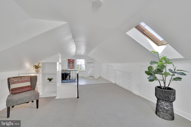 sitting room with vaulted ceiling with skylight and carpet flooring