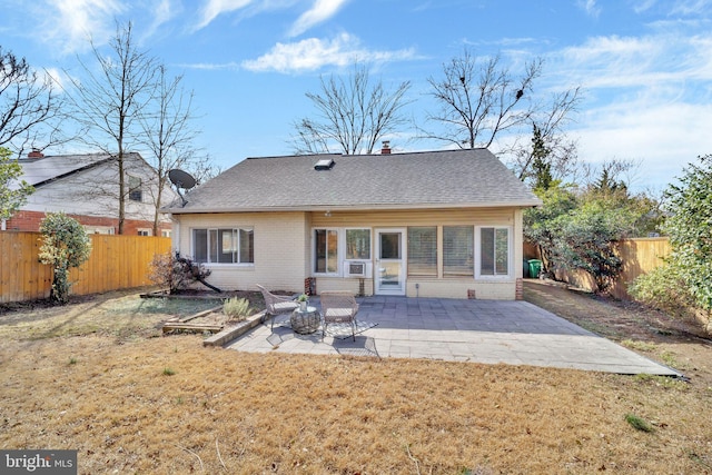 rear view of house featuring a fenced backyard, roof with shingles, a yard, a patio area, and brick siding