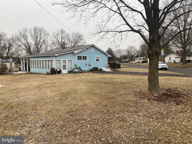 view of property exterior featuring a sunroom and a lawn