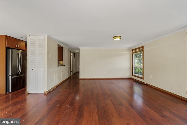 unfurnished living room with dark wood-type flooring, baseboards, and crown molding