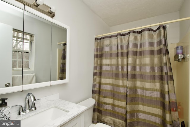 bathroom with a textured ceiling, toilet, vanity, and a shower with curtain