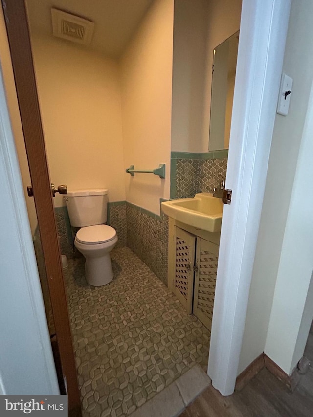 bathroom featuring sink, tile walls, and toilet