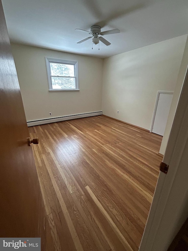 unfurnished bedroom featuring hardwood / wood-style flooring, a baseboard radiator, and ceiling fan