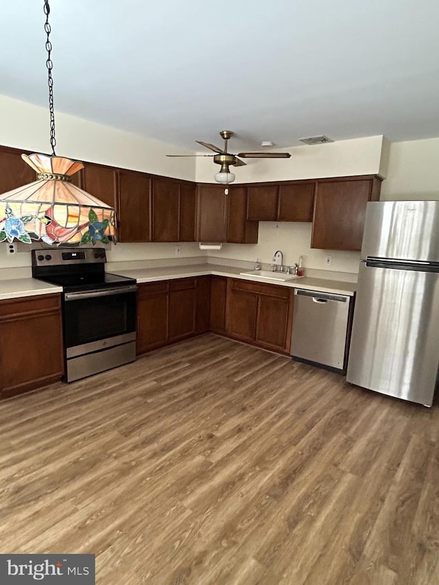 kitchen featuring stainless steel appliances, hanging light fixtures, sink, and hardwood / wood-style floors