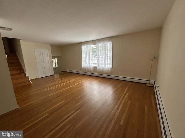 unfurnished living room featuring hardwood / wood-style floors and a baseboard heating unit