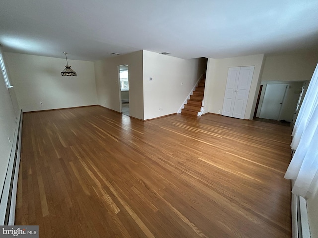 unfurnished living room with hardwood / wood-style flooring and a baseboard radiator