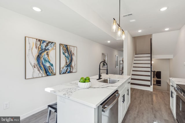 kitchen with visible vents, white cabinets, wood finished floors, stainless steel appliances, and a sink