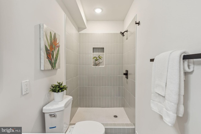 full bathroom featuring a tile shower and toilet