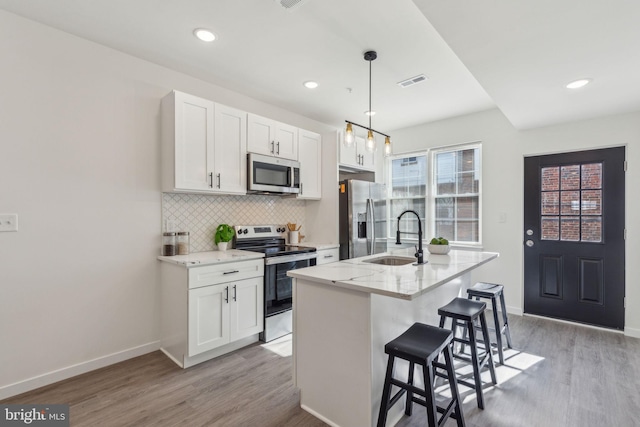 kitchen featuring visible vents, light wood-style flooring, appliances with stainless steel finishes, a sink, and backsplash