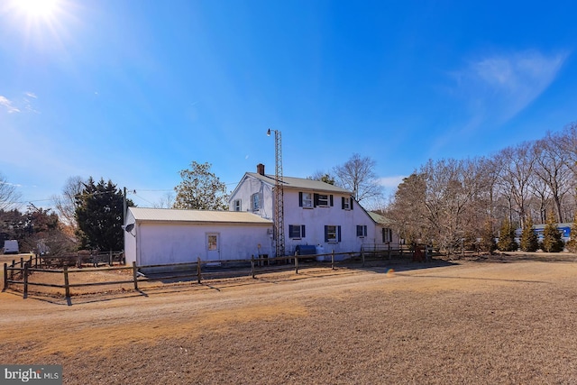 rear view of property with fence, a chimney, and metal roof