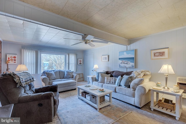 living area featuring heating unit, carpet flooring, crown molding, and a ceiling fan