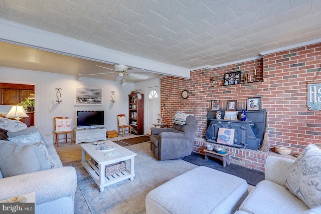 living room with beam ceiling, brick wall, carpet flooring, ceiling fan, and a wood stove