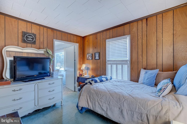 carpeted bedroom featuring wooden walls and crown molding