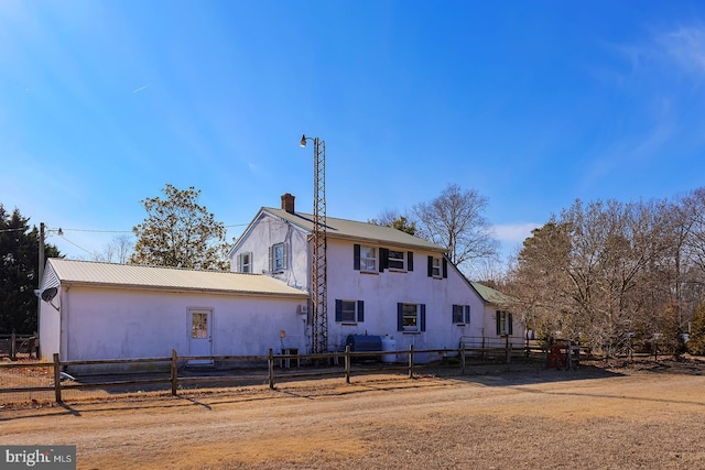 view of front facade featuring fence, a chimney, and metal roof