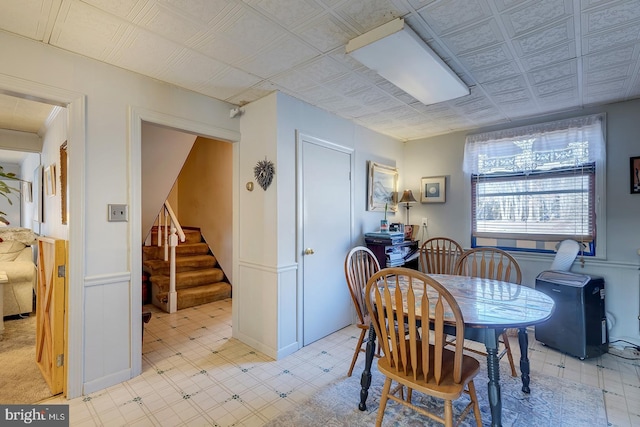 dining area featuring a wainscoted wall, light floors, an ornate ceiling, and stairs