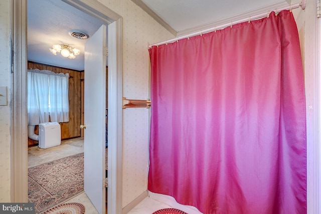 bathroom with wallpapered walls, visible vents, and ornamental molding