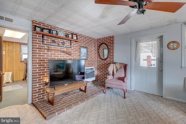 carpeted living room featuring wooden walls, heating unit, visible vents, and a wealth of natural light