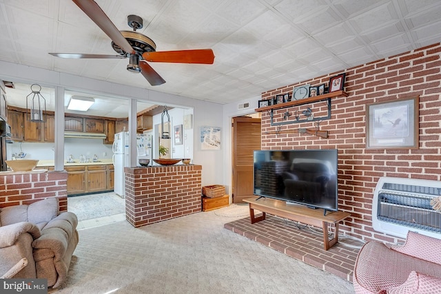 living area featuring heating unit, a ceiling fan, visible vents, brick wall, and light colored carpet