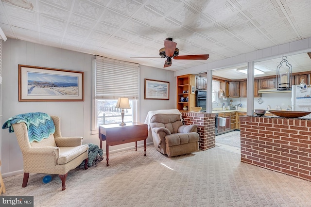 living area featuring light carpet and ceiling fan