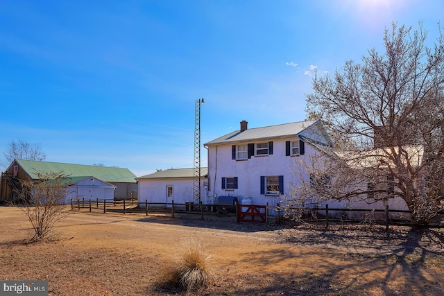 back of house featuring a chimney and fence