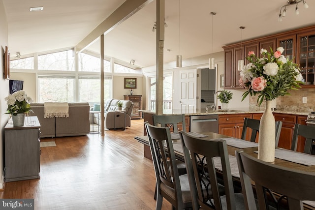 dining area featuring sink, wood-type flooring, high vaulted ceiling, and beamed ceiling