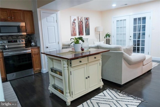 interior space with appliances with stainless steel finishes, backsplash, cream cabinets, dark hardwood / wood-style flooring, and french doors