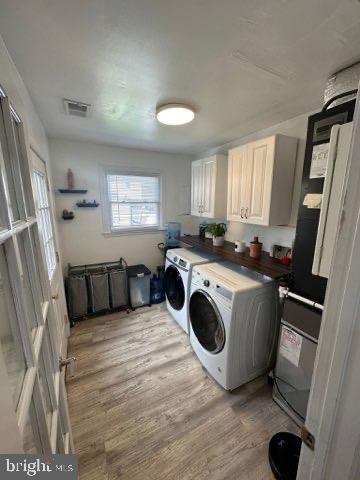 washroom with cabinets, light hardwood / wood-style flooring, and washer and dryer