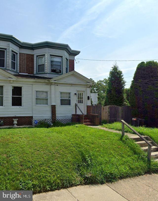 view of side of home with fence and a lawn