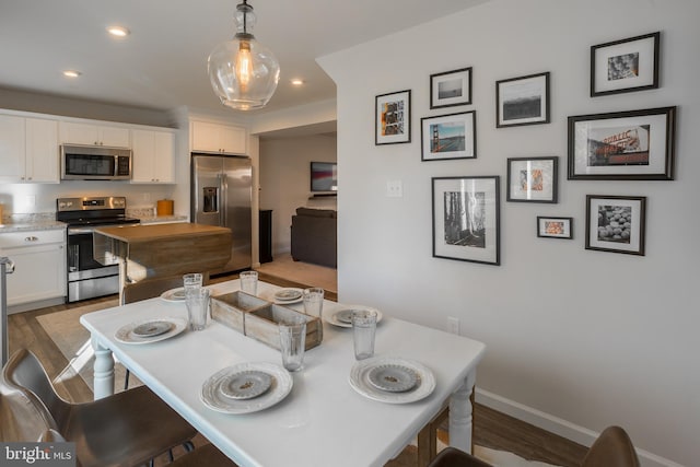 kitchen featuring white cabinets, decorative light fixtures, stainless steel appliances, light wood-type flooring, and recessed lighting