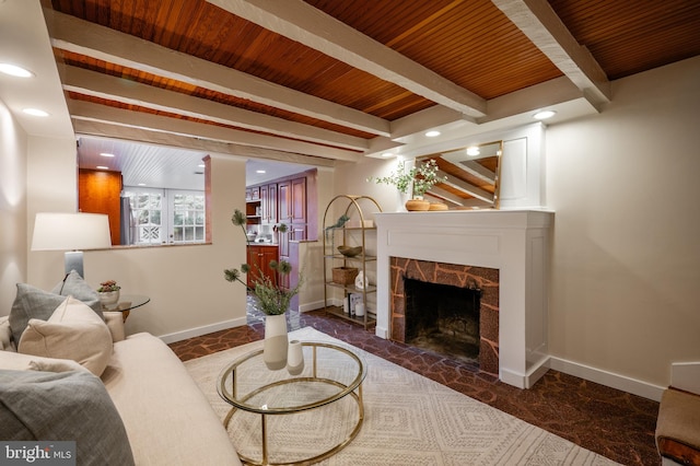 living area with beamed ceiling, baseboards, a fireplace, and wood ceiling