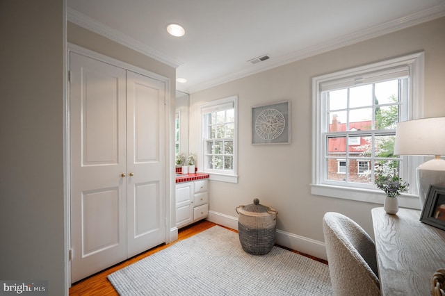 sitting room featuring crown molding, wood finished floors, visible vents, and a wealth of natural light