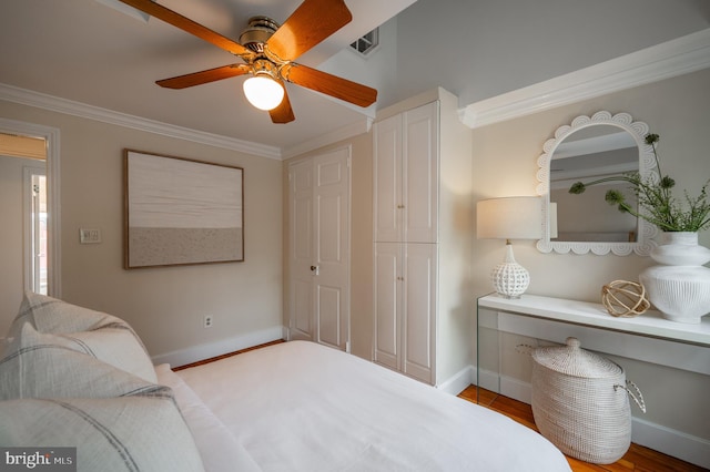 bedroom featuring crown molding, wood finished floors, baseboards, and visible vents