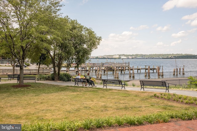 dock area featuring a water view, fence, and a lawn