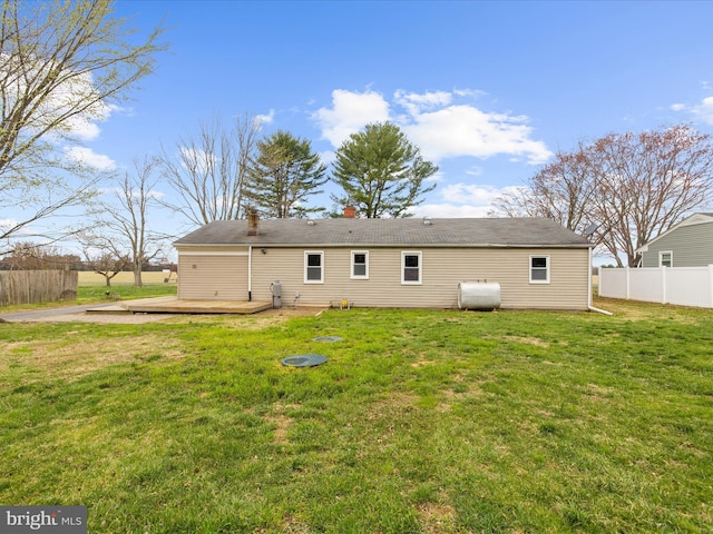 back of property featuring a yard, heating fuel, fence, and a wooden deck