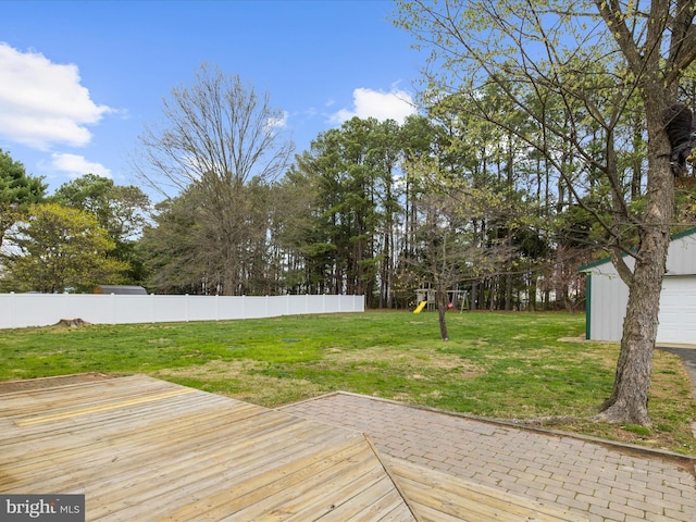 wooden deck featuring a playground, a yard, and fence