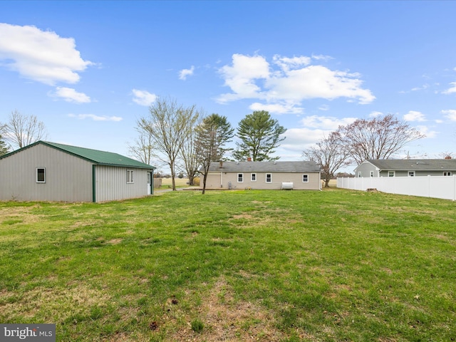 view of yard with an outdoor structure, a pole building, and fence