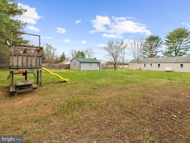 view of yard featuring a playground, an outbuilding, and fence