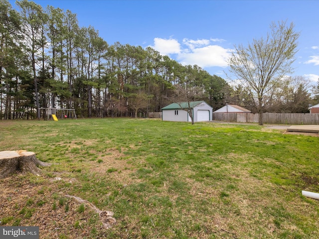 view of yard with an outdoor structure, fence, a garage, and a playground