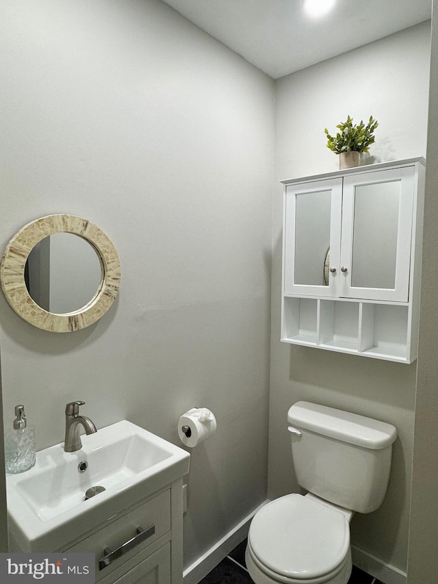 half bath featuring toilet, a sink, and baseboards