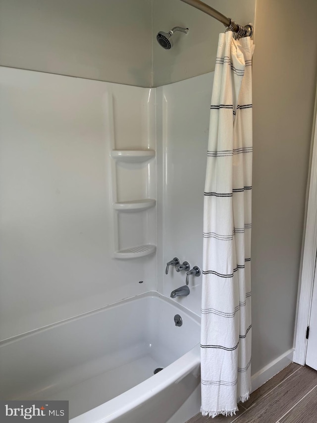full bathroom featuring baseboards, shower / tub combo, and wood finished floors
