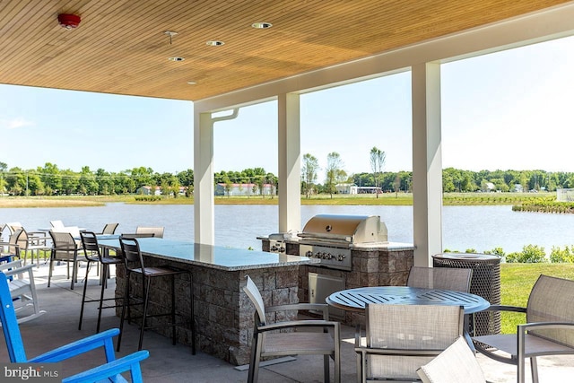 view of patio with a water view, a grill, outdoor dry bar, and area for grilling