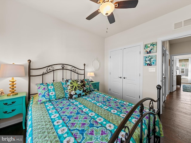 bedroom with dark wood-type flooring, a closet, visible vents, and a ceiling fan