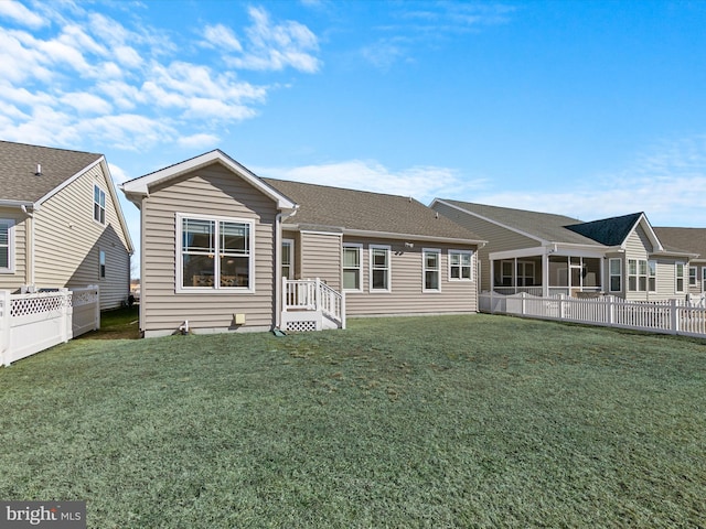 rear view of property with a lawn and fence