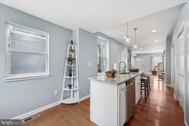 kitchen with sink, decorative light fixtures, stainless steel dishwasher, an island with sink, and white cabinets