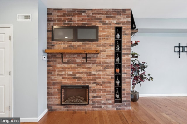 interior details with wood-type flooring and a brick fireplace