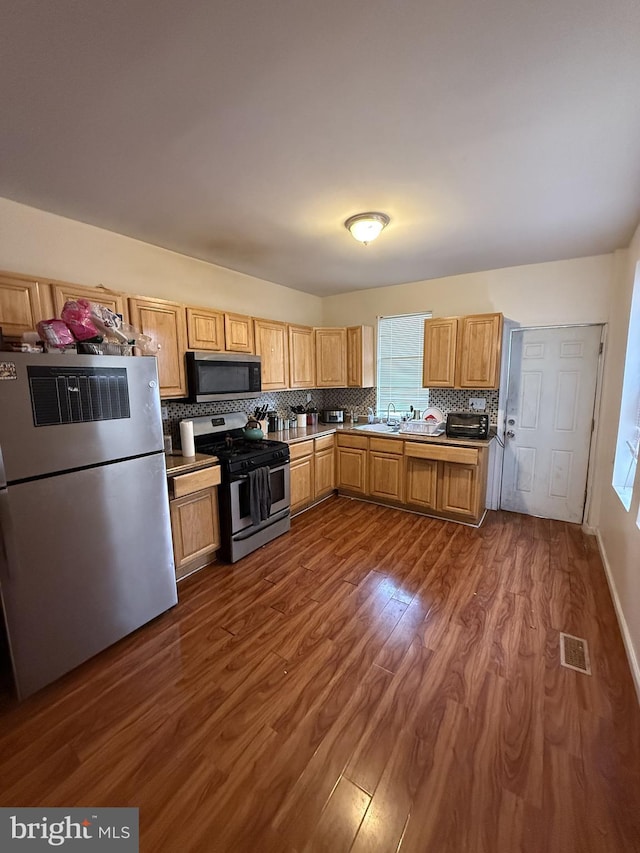 kitchen featuring stainless steel appliances, dark hardwood / wood-style floors, sink, and decorative backsplash